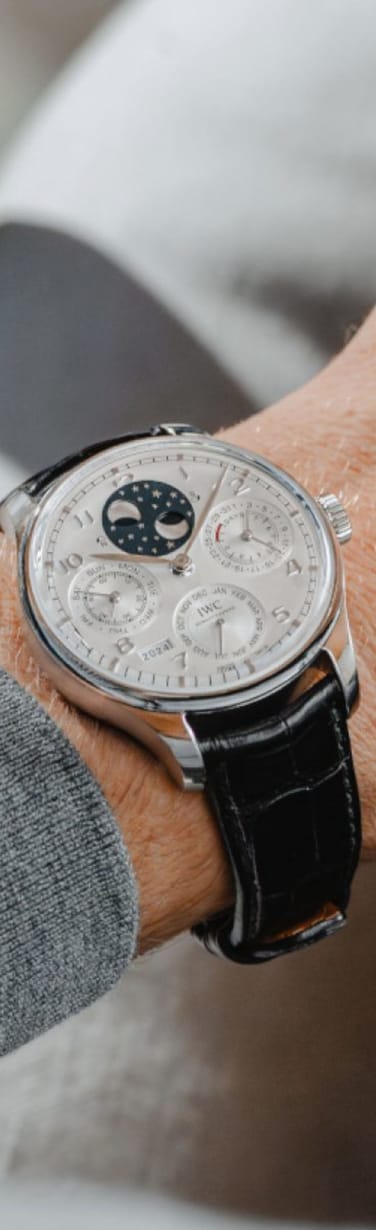 Close-up of a male wrist wearing IWC perpetual calendar with a black leather strap
