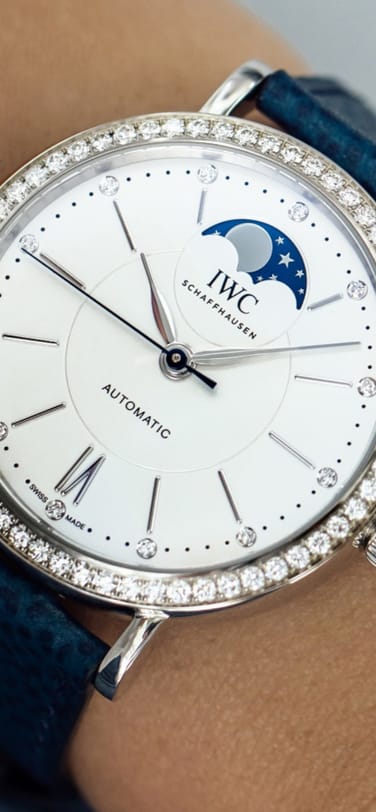 Close-up of a watch featuring a moon phase and diamonds on the bezel